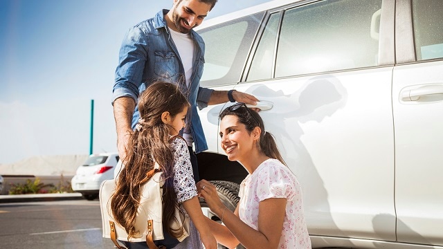 Young family in Dubai - UAE, taking their little girl to school by car in the morning in Jumeirah district. They are happy in a sunny day.