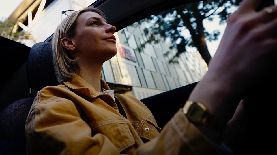 Mujer con una chaqueta amarilla conduciendo un auto.