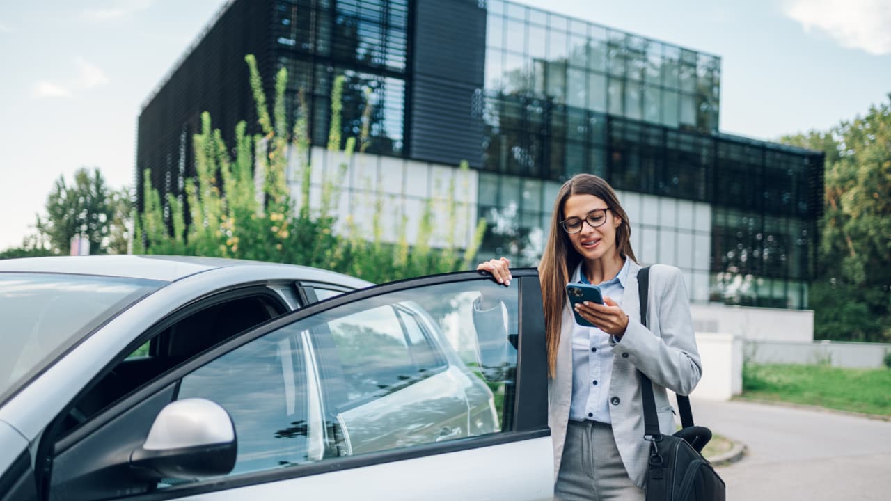 Mujer en su teléfono entrando en un auto.