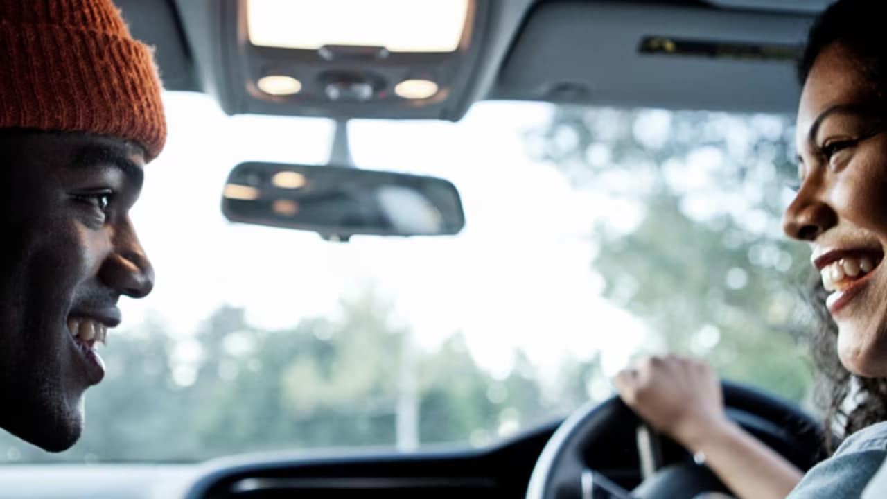Primer plano de un hombre y una mujer hablando en un auto.
