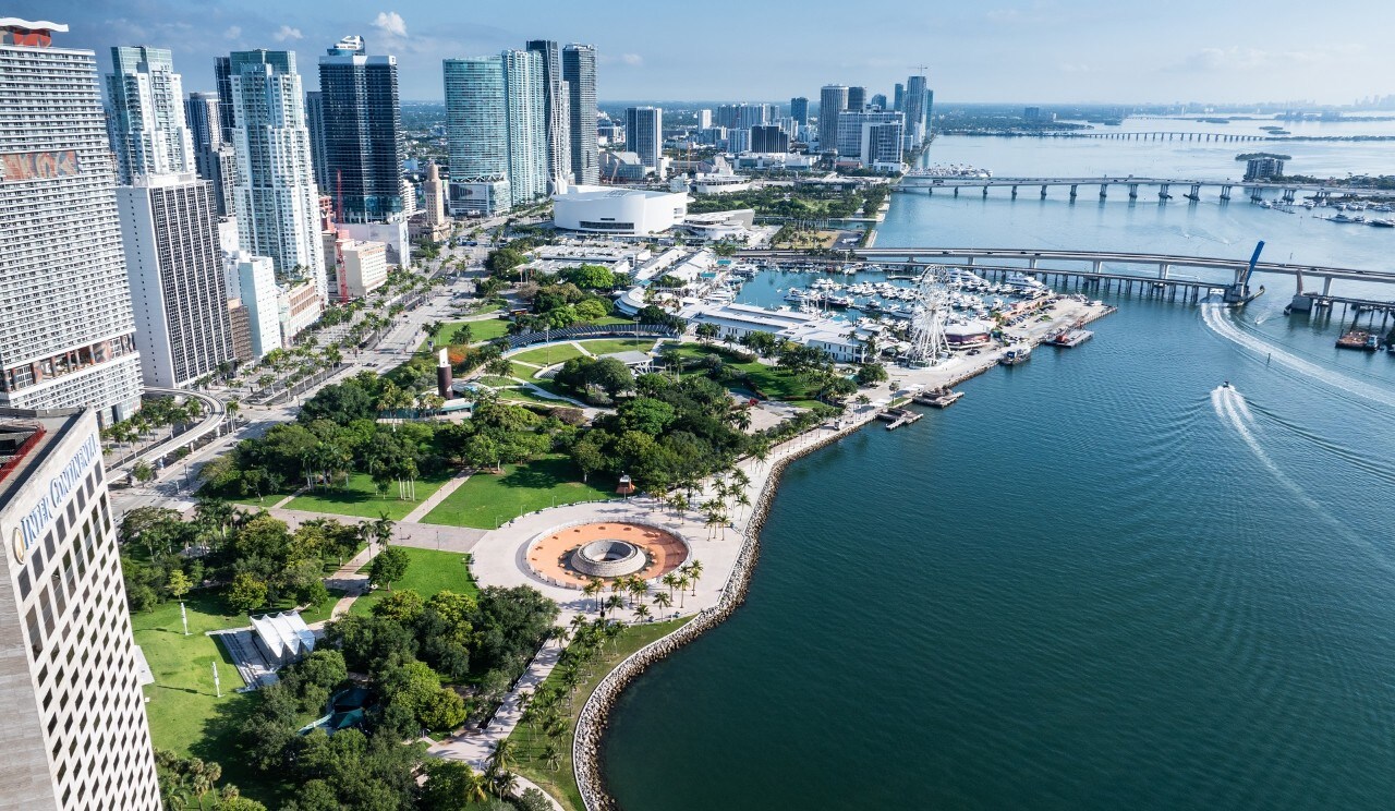 This aerial drone shot of Miami and Biscayne Bay allows us to see into the many aspects of Miami lifestyle and the options for entertainment when travelling.  There is a massive condominium complex, harbors with countless boats and yachts, a beautiful boardwalk, and so much entertainment.  In this photo alone, we see a huge ferris wheel on the boardwalk, as well as jetskis cruising around the bay.  Not to mention the multiple islands connecting to Miami's stunning cityscape full of skyscrapers.